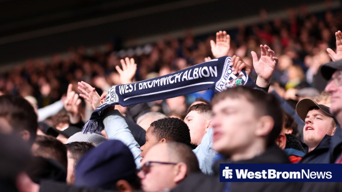 West Brom fans hold a club scarf aloft.
