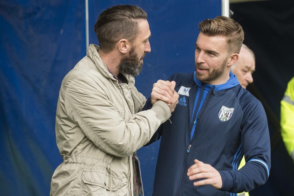 West Brom coach James Morrison shakes hands with a counterpart ahead of a game.